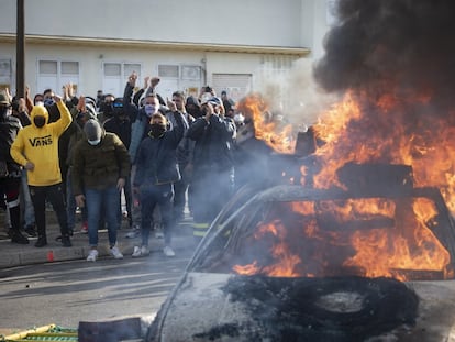 Varios trabajadores protestan junto a un coche ardiendo en las protestas a la entrada de la sede de Navantia en Cádiz.