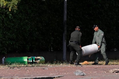 Dos integrantes de las Fuerzas Armadas trasladan cilindros sin detonar hallados en la zona del atentado.