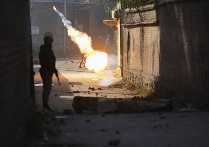 Un policía indio observa como estalla una bomba de humo cerca de un manifestante, en Srinagar (India).