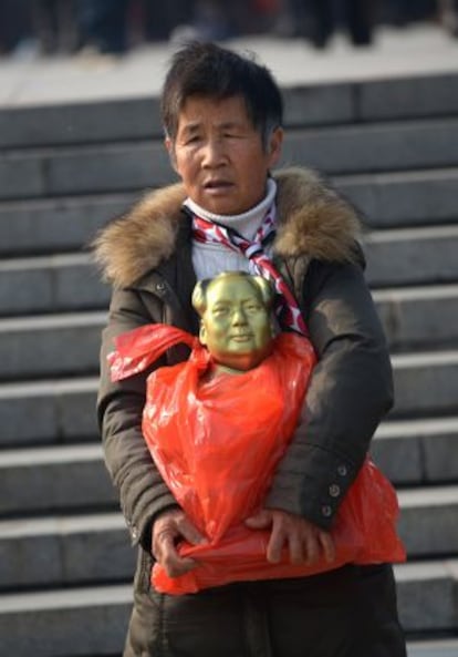 Uma anciã, com una estátua de Mao em bronze.