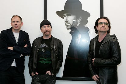 El cantante de U2, Bono; su guitarrista, The Edge; y el fotógrafo Anton Corbijn posan (de derecha a izquierda) frente a una de las imágenes de la exposición sobre el grupo inaugurada en la galería Stellan Holm de Nueva York.