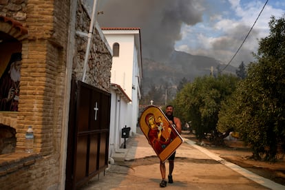 Un hombre transporta a la virgen para evitar que se queme, en un monasterio de Acarnas, este miércoles. 