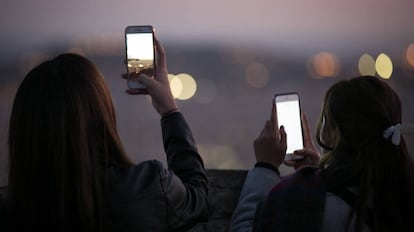 Dos j&oacute;venes toman im&aacute;genes con sus m&oacute;viles en Barcelona. 