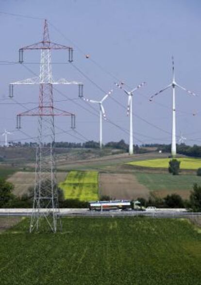 Tendido eléctrico con aerogeneradores eólicos de fondo.