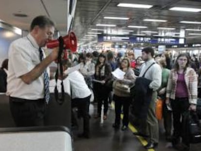 En la imagen, un trabajador de Aerolíneas Argentinas habla a través de un megáfono a los viajeros que se ven afectados por el retraso de los vuelos. EFE/Archivo