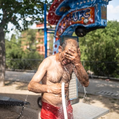 Jose (56 años) se refresca con una manguera después de haber estado toda la mañana reparando y poniendo a punto la atracción de los coches de choque en la feria de San Isidro.

