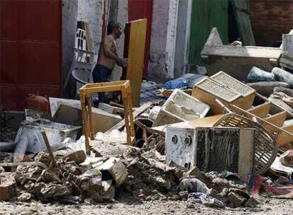 Un cosladeño recoge los muebles esparcidos en la calle durante la riada del lunes.