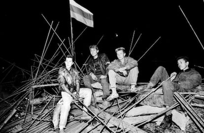 Jovens se sentam sob uma bandeira russa em uma barricada diante da Casa Branca Russa, no coração de Moscou, na madrugada de 20 de agosto de 1991.