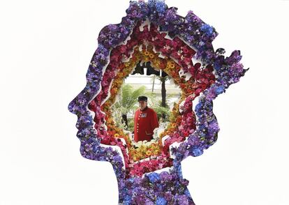 Un jubilado de Chelsea posa detrás de la instalación floral con la silueta de la reina Isabell II de Inglaterra titulada 'Detrás de cada gran florista', diseñada por Veevers Carter, durante la Exposición de Flores de Chelsea, en Londres (Reino Unido).