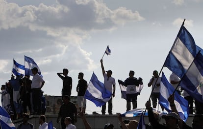 Los manifestantes han portado banderas y han gritado al unísono "¡presidente, márchese!" a su avance por la capital. En la imagen, un grupo de personas portan la bandera nacional de Nicaragua durante la protesta en Managua.
