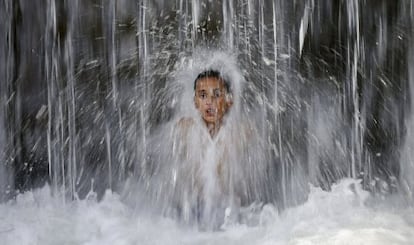 Un niño se baña bajo una cascada en Kabul (Afganistán).