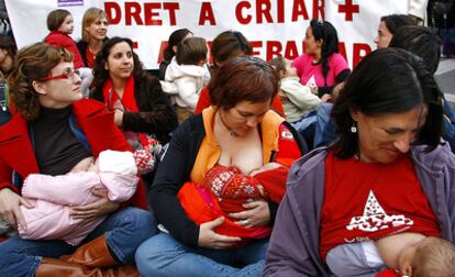 Unas mujeres amamantana sus hijos en Valencia ante una pancarta que reclama su derecho a trabajar y a criar.