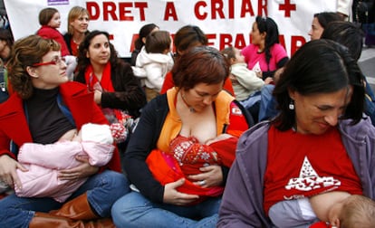 Unas mujeres amamantana sus hijos en Valencia ante una pancarta que reclama su derecho a trabajar y a criar.