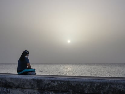 Una mujer contempla la tormenta de arena del Sáhara desde el Malecón de La Habana, Cuba.