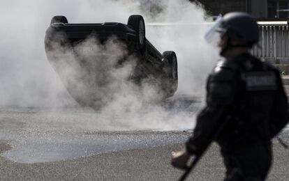 An UberPop vehicle is upside down and set on fire during a taxi driver protest against the company, in Paris.