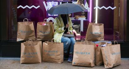 Una mujer rodeada por bolsas de Primark frente a una tienda en Londres.