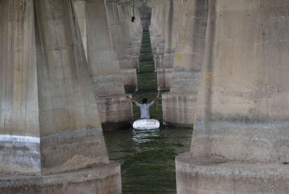 Un joven en una balsa improvisada por el río Sabarmati en Ahmedabad, usando un imán recoge unos 400 INR (unos 6,60 dólares) en monedas lanzadas al agua por los devotos como ofrendas.