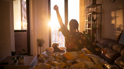 Una chica desperezándose por la mañana en su cama con la salida del sol.