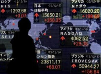 Un empresario pasa por delante de una pantalla con la cotizaci&oacute;n de la Bolsa de Tokio.