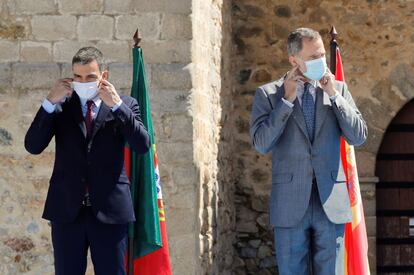El presidente del Gobierno, Pedro Sánchez (izquierda) y el rey Felipe VI, se ponen las mascarillas antes de la foto oficial en Elvas (Portugal). Con este acto, ambos gobiernos han querido escenificar la importancia que conceden a la reapertura de la frontera, cerrada desde el 17 de marzo por la pandemia de coronavirus.