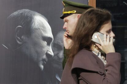 Varias personas caminan frente al poster de un libro llamado 'Entrevista con Vladimir Putin' del estadounidense Oliver Stone, en una tienda de San Petersburgo, el 25 de septiembre de 2017.  