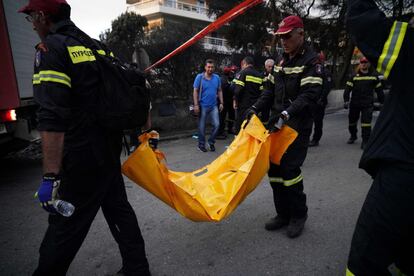 Los bomberos trasladan el cuerpo sin vida de una persona tras el incendio forestal en la aldea de Mati, cerca de Atenas. La cifra de muertos asciende a 70 personas.