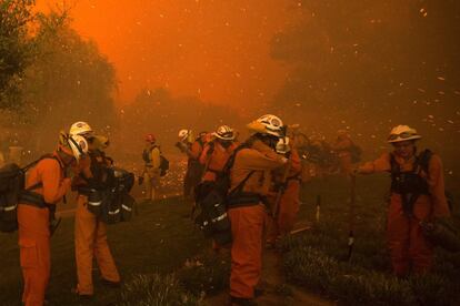 Unos 300 bomberos están combatiendo las llamas. En la imagen, un grupo de bomberos se protegen de las llamas cerca de Santa Clarita, California.