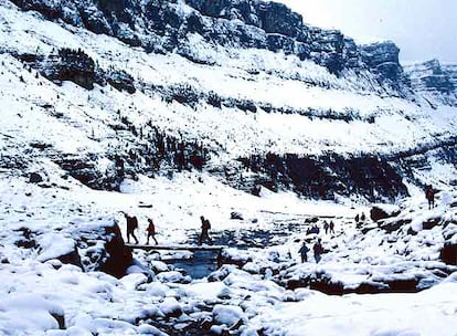 Excursionistas cruzan el río Arazas, en el valle de Ordesa. Un recorrido invernal por este rincón de los Pirineos puede llevar a paisajes tan espectaculares como el de la cascada de la Cola de Caballo.