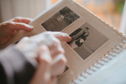 Una persona consulta, con un familiar, un álbum de fotos.