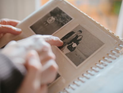 Una persona consulta, con un familiar, un álbum de fotos.