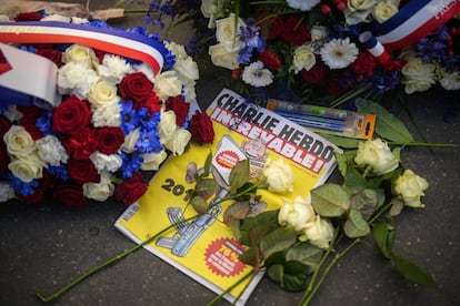 Un ejemplar de la edición especial de 'Charlie Hebdo', publicada 10 años después del atentado, rodeado de flores frente a la antigua redacción de la revista. 