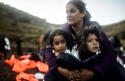 Uma mãe abraça a seus filhos após desembarcar na ilha grega de Lesbos, depois de cruzar o mar Egeo vindo da Turquia, em 19 de novembro de 2015.