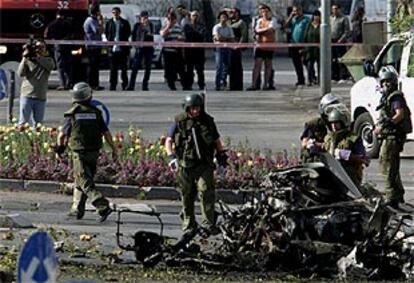 Agentes de la policía israelí examinan los restos de un coche bomba que estalló ayer junto a un centro comercial de la zona judía de Jerusalén.