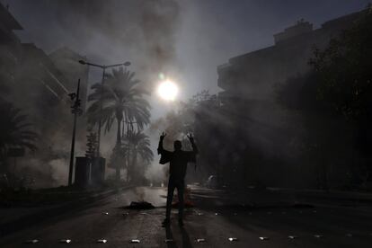 Un manifestante muestra el signo de la victoria, mientras otros queman neumáticos para bloquear una carretera frente a la casa del juez Fadi Akiki durante una manifestación que pide la liberación de los activistas antigubernamentales detenidos tras los disturbios en el norte del Líbano a finales del mes pasado, en Beirut, Líbano.