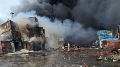 Varios bomberos trabajan en las labores de extinción del incendio que se ha originado en el puerto de Bandar Abás, este domingo.