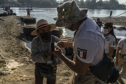 Un miembro del Instituto Nacional de Migración de México revisa los documentos de un guatemalteco en la orilla del río Suchiate, en la frontera entre México y Guatemala.