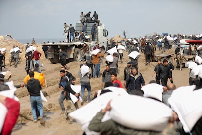 Palestinos cargan bolsas de harina que cogieron de un camión de ayuda humanitaria cerca de un puesto de control israelí, en la ciudad de Gaza, el 19 de febrero.