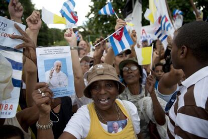 Una mujer muestra una foto del Papa mientras espera el paso del papam&oacute;vil en una carretera de las inmediaciones del aeropuerto de La Habana.