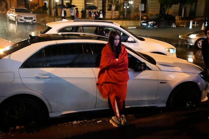 Final de fiesta: una joven, arropada con la bandera de Marruecos, se apoya en un coche aparcado en una calle de Rabat.  