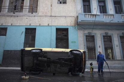 Un mecánico limpia los bajos de un coche en una calle de la Habana (Cuba).