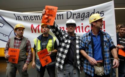 Varios trabajadores de la constructora alemana ante una pancarta que reza "en memoria de Dragados, con nosotros no" y con carteles de "ACS, no".