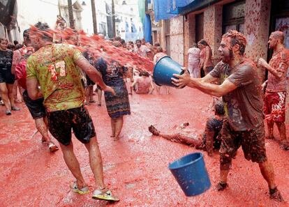 Un participante vierte un cubo lleno de tomate a otro durante la fiesta.