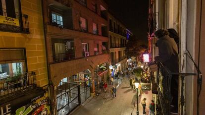 Vecinos de Malasaña contemplan desde un balcón el bullicio en la calle Velarde. 
 