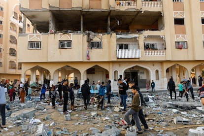 People walk at the site of an Israeli strike on the apartment building, amid the ongoing conflict between Israel and Palestinian Islamist group Hamas, in Khan Younis in the southern Gaza Strip, November 18, 2023.