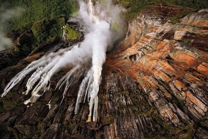 En octubre de 1982, el fotógrafo venezolano Rodolfo Gerstl (www.rodolfogerstl.com), autor de la foto, realizó el primer salto base en paracaídas desde lo alto del Salto Ángel, la cascada más alta del mundo (alcanza los 807 metros de caída ininterrumpida), a la que le ha dedicado su libro Ángel (de venta en Amazon y en librerías como Desnivel y Antonio Machado). Gerstl ha sido durante muchos años guía especializado en esta cascada, sobrevolándola en helicóptero con los visitantes. Situada en el parque nacional venezolano de Canaima, en las mesetas rocosas conocidas como tepuyes, la cascada lleva su nombre por Jimmy Angel, el aviador estadounidense que en 1937 consiguió posarse en la cima del Auyan-Tepuy (2.400 metros), donde nace. “Cada vez que viajas allí la naturaleza te enseña algo nuevo”, dice Rodolfo Gerstl, “ya sea en el agua, con sus colores y reflejos en las paredes del tepuy; ya sea en las texturas de las formaciones rocosas, o hasta en el aire, con sus formaciones de nubes. Allí sientes claramente lo pequeños que somos”.