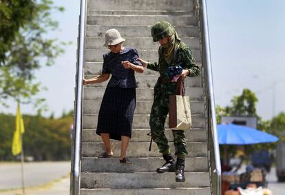 Un soldado ayuda a una anciana bajar unas escaleras en el centro de Bangkok (Tailandia). El ejército de Tailandia inició una ronda de contactos con representantes del Gobierno, instituciones y manifestantes para encontrar una salida negociada a la crisis política, un día después de declarar la ley marcial.