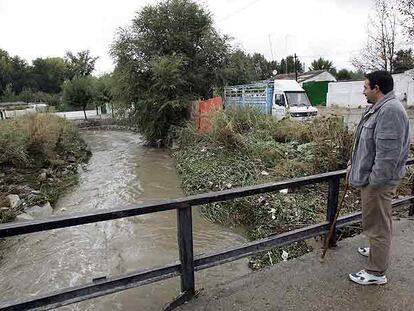 Un vecino observa el río Guadarrama junto a las viviendas, en Móstoles.