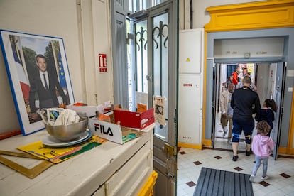 Un retrato del presidente francés Macron en primer término cuando los votantes llegan a una mesa electoral durante la segunda ronda de las elecciones parlamentarias francesas en París, Francia.