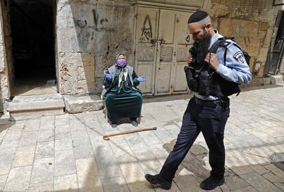 Un policía israelí pasa frente a una palestina que reza cerca de la Explanada de las Mezquitas, este viernes en Jerusalén.