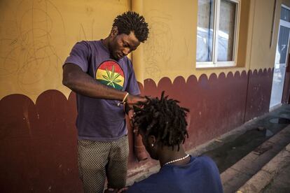 Un joven africano trenza el pelo de un compañero en el CETI, el centro donde son atendidos por la Cruz Roja a su llegada a Melilla.